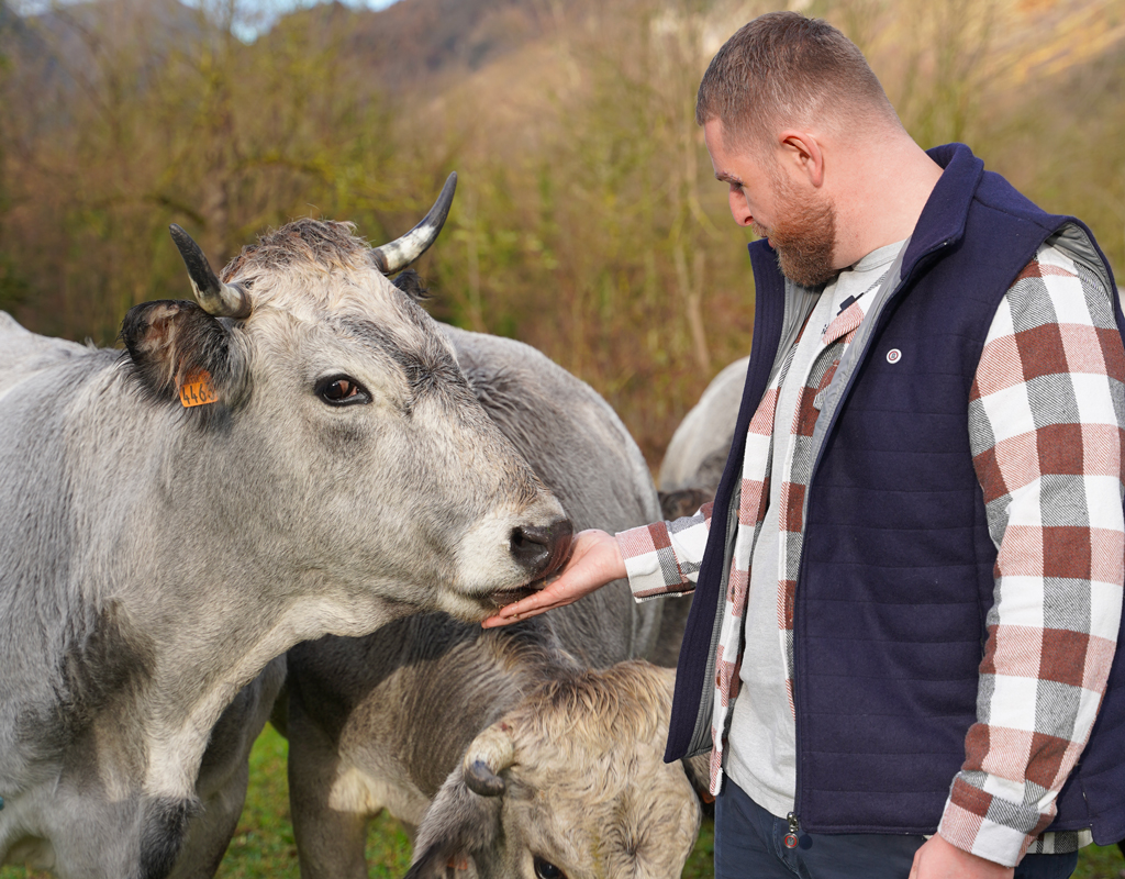 Bastien avec un vache dans un champ en Ariège